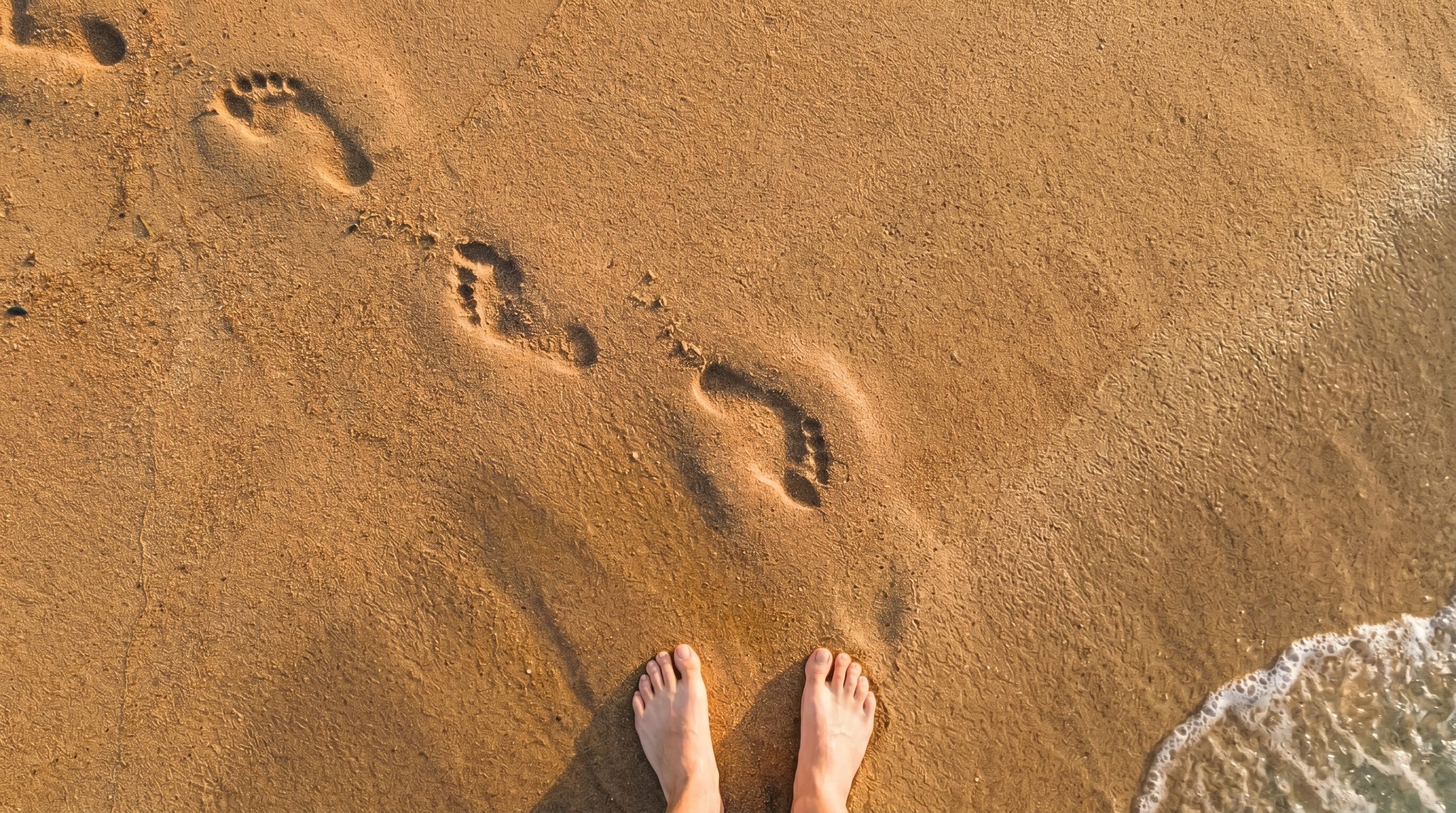 Plan rapproché aérien sur des pieds nus marchant dans le sable mouillé près de l'eau, fin du parcours